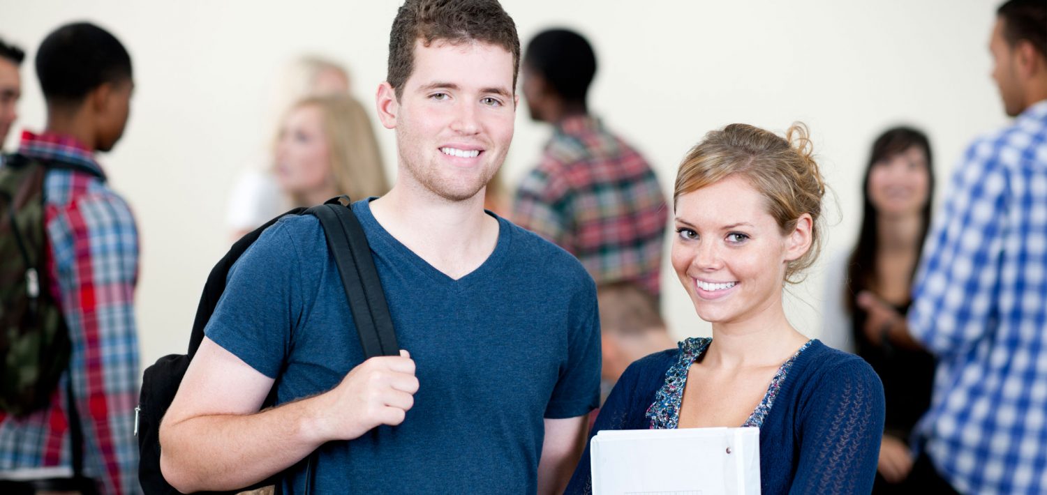 Two students standing outside of class smiling.