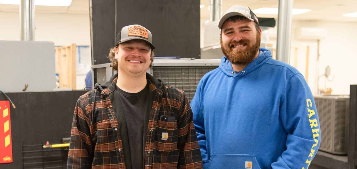 Two HVAC students smile for a picture in the HVAC lab