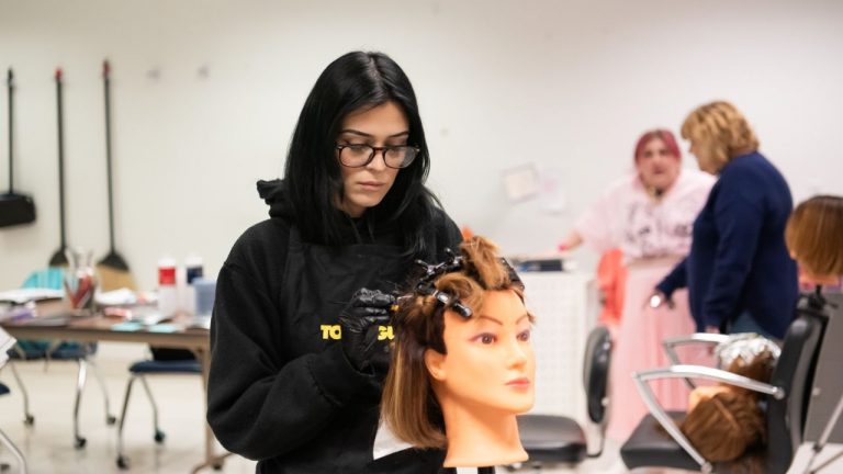 A Penn Commercial cosmetology student styles a head of hair