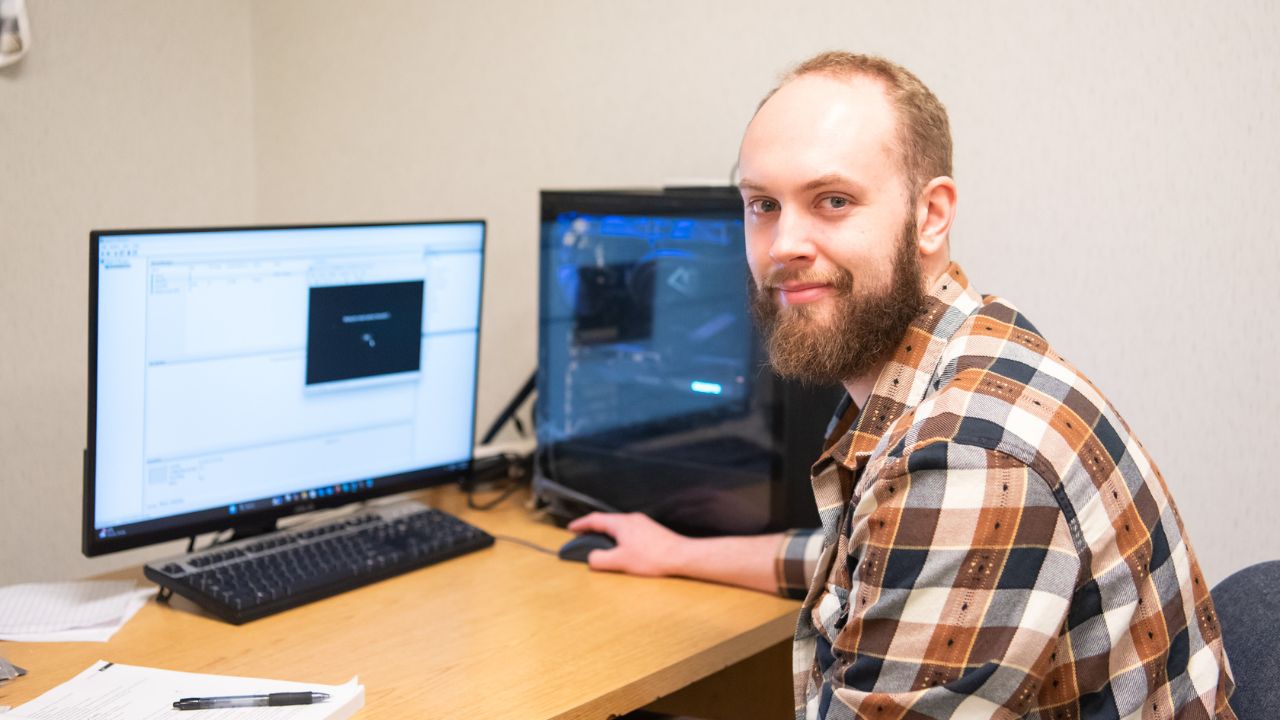 A Penn Commercial Information Technology and Security student smiles for a picture in front of a computer