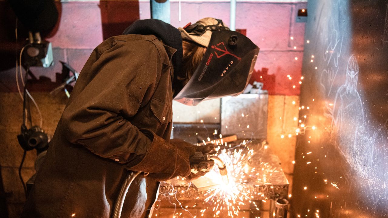 A Penn Commercial welding student is captured mid-weld with sparks flying