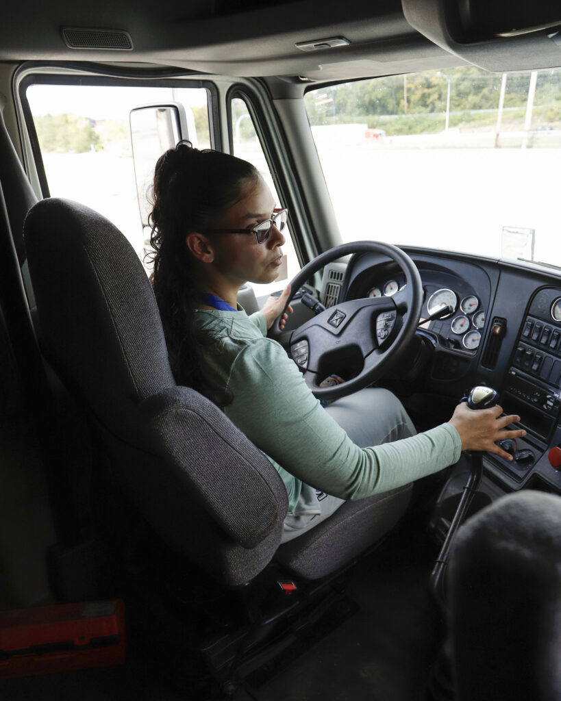 Penn Commercial CDL student behind the wheel of a training truck, hands on the steering wheel and gear shifter.
